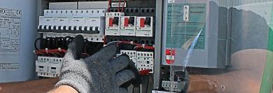 Image of a gloved hand working on an electrical panel